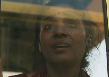 A young woman looks out a window terrified in the movie Yellow Bus.