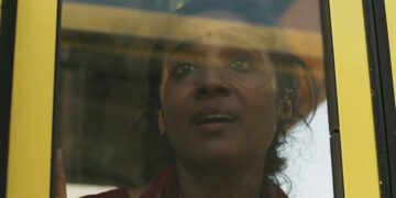 A young woman looks out a window terrified in the movie Yellow Bus.