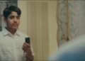Atharv Verma as Illyas staring in the mirror holding an electric razor in the movie Mustache.