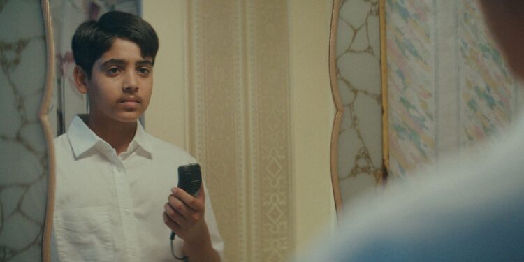 Atharv Verma as Illyas staring in the mirror holding an electric razor in the movie Mustache.