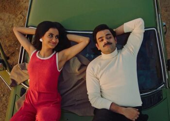 Amrit Kaur as Azra and Hamza Haq as Hassan laying next to each other on the hood of a green car in the Canadian movie The Queen of My Dreams