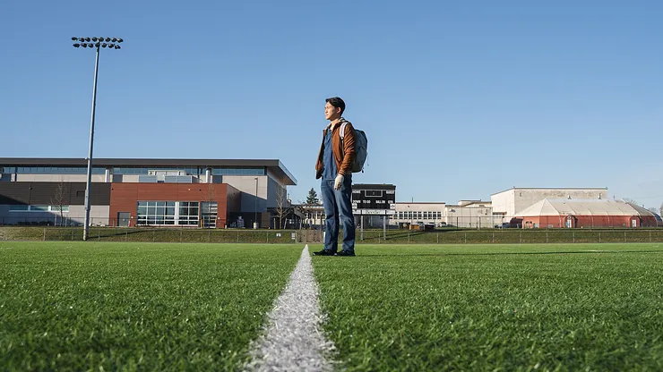 Jake standing alone in a high school football field from Golden Delicious