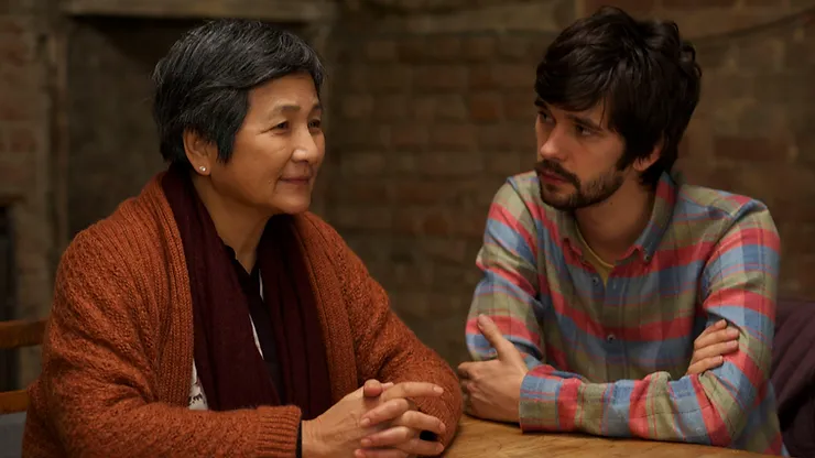 Cheng Pei-pei as Junn and Ben Whishaw as Richard sit next to each other at a table in the movie Lilting.