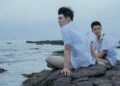 Edward Chen as Chang Jia-han and Jing-hua Tseng as Wong Po Te, sitting on a rocky beach, in Your Name Engraved Herein.