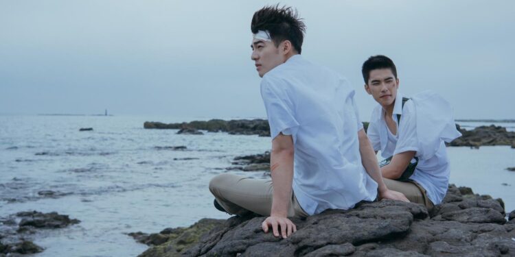 Edward Chen as Chang Jia-han and Jing-hua Tseng as Wong Po Te, sitting on a rocky beach, in Your Name Engraved Herein.