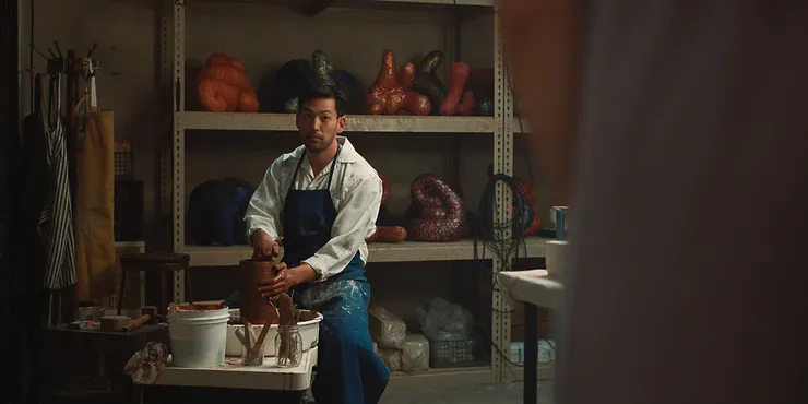 Joseph Lee as George Nakai sitting at a potter's wheel in the Netflix series BEEF.