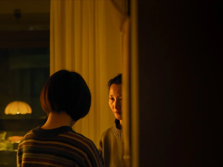 Two women staring at each other in a dimly lit room from the movie Some Rain Must Fall.