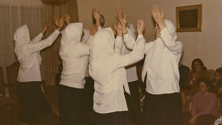A group of young women with their arms raised up in praise - a photo still from Jude Chehab's movie, Q