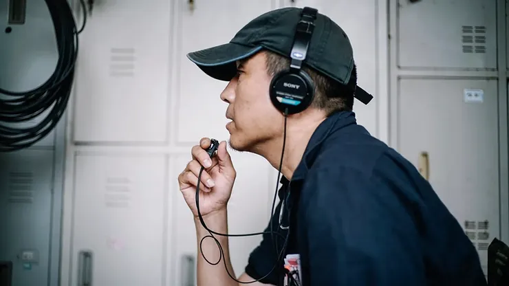 Director Lou Ye in side profile speaking into a small mic in Unfinished Film.