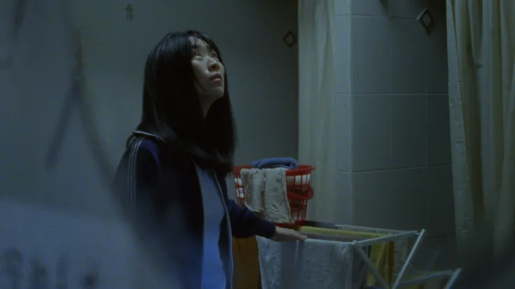 Wu Ke-xi as Amy standing next to a drying rack and laundry in Blue Sun Palace.