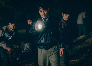 Zhu Yilong as Ma Zhe holding a flashlight investigating a scene in the Only the River Flows.