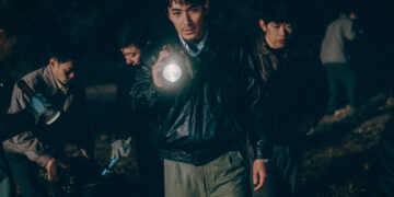 Zhu Yilong as Ma Zhe holding a flashlight investigating a scene in the Only the River Flows.