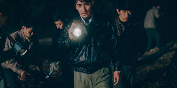 Zhu Yilong as Ma Zhe holding a flashlight investigating a scene in the Only the River Flows.