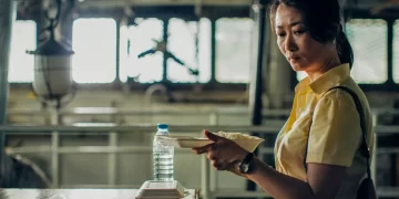 A tear rolls down Zhao Tao's face as she holds a takeout container of rice in Caught by the Tides.