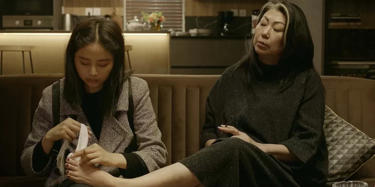 Sitting on a couch, Bayarjargal Bayartsetseg as Saruul wraps the big toe of Oidovjamts Enkhtuul as Katya in The Sales Girl