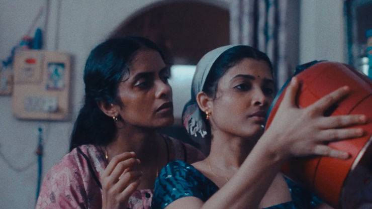 Kani Kusruti as Prabha and Divya Prabha as Anu looking into a red cannister in All We Imagine as Light.