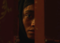 Ramesha Nawal as Mariam staring behind a door from the movie In Flames.