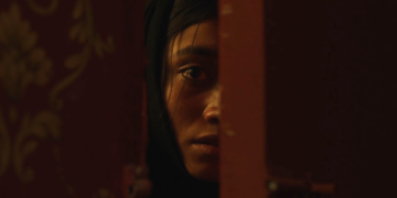 Ramesha Nawal as Mariam staring behind a door from the movie In Flames.