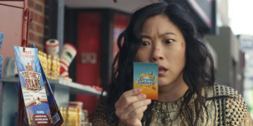 Awkwafina as Katie Kim staring at a lottery ticket in the movie Jackpot.
