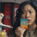 Awkwafina as Katie Kim staring at a lottery ticket in the movie Jackpot.