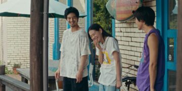 Hiroki Sano as Sano standing with two friends in front of a house laughing in Super Happy Together.