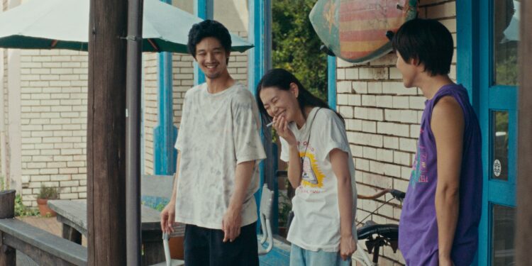 Hiroki Sano as Sano standing with two friends in front of a house laughing in Super Happy Together.