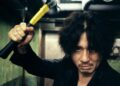 Choi Min-sik as Oh Dae-su wields a hammer in a hallway from Oldboy.