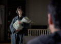 Jung Yu-mi as Soo-ji holds her baby and looks at her husband Hyun-su, played by Lee Sun-kyun
