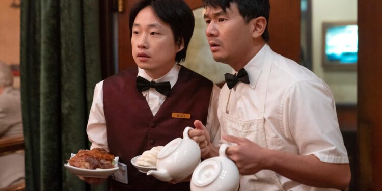 Jimmy O. Yang as Willis Wu and Ronny Chieng as Fatty Choi holding plates and tea pots in the television series Interior Chinatown.