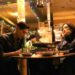 Kim Go-eun as Jae-hee and Steve Sanghyun Noh as Heung-soo sit in a dimly lit Korean restaurant in Love in the Big City.