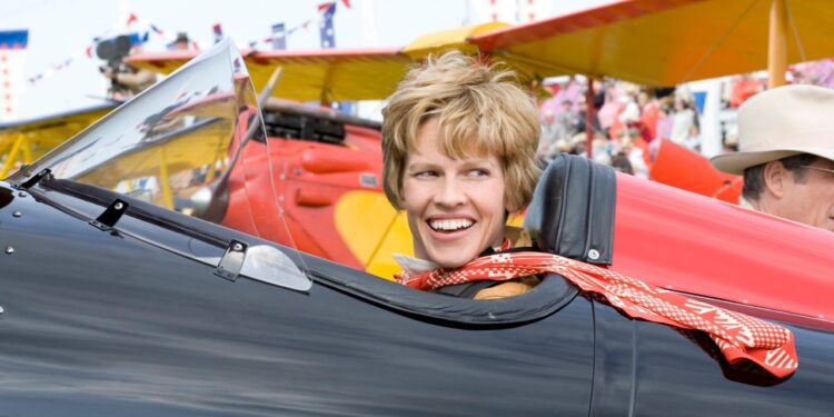 Hilary Swank as Amelia Earhart seated in a black airplane in Amelia