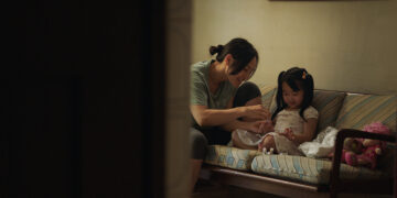 Thi Diu Ta as Hanh and Aster Yeow Ee as Ting Ting sit on a sofa smiling in Oasis of Now.