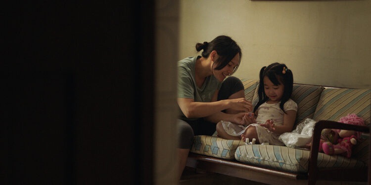 Thi Diu Ta as Hanh and Aster Yeow Ee as Ting Ting sit on a sofa smiling in Oasis of Now.