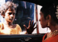 Shafiq Syed as Krishna looking into a car in Salaam Bombay!