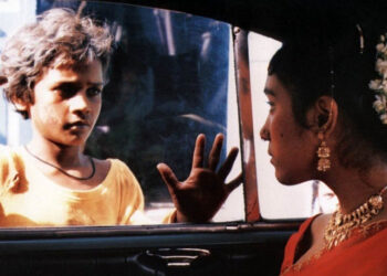 Shafiq Syed as Krishna looking into a car in Salaam Bombay!