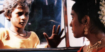 Shafiq Syed as Krishna looking into a car in Salaam Bombay!