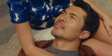 Henry Golding as Nicholas laying in the lap of his partner in Daniela Forever