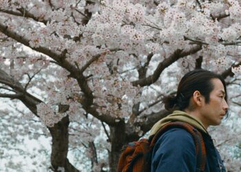 Mirai Moriyama as Takashi Toyama walking past a cherry blossom tree in Great Absence