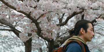 Mirai Moriyama as Takashi Toyama walking past a cherry blossom tree in Great Absence