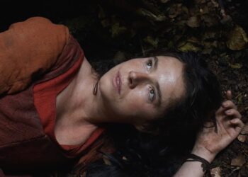 Jessie Buckley, as Agnes, lies on a forest floor in the opening scene of Hamnet.