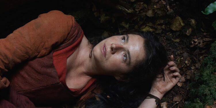 Jessie Buckley, as Agnes, lies on a forest floor in the opening scene of Hamnet.