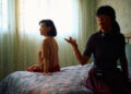 Joan Chen and Xiaodan He sitting on a bed behind the scenes of Montreal ma belle