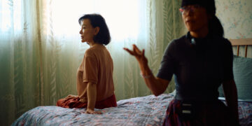 Joan Chen and Xiaodan He sitting on a bed behind the scenes of Montreal ma belle