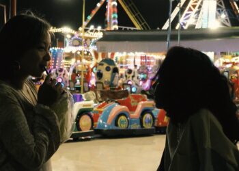 Sopheanith Thong and Deka Nine as Nisay and Thida in Whisperings of the Moon, having an intimate conversation at an amusement park.