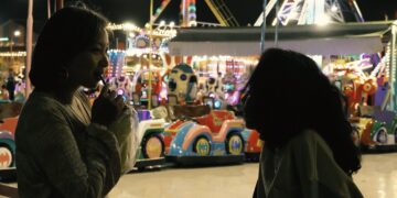 Sopheanith Thong and Deka Nine as Nisay and Thida in Whisperings of the Moon, having an intimate conversation at an amusement park.
