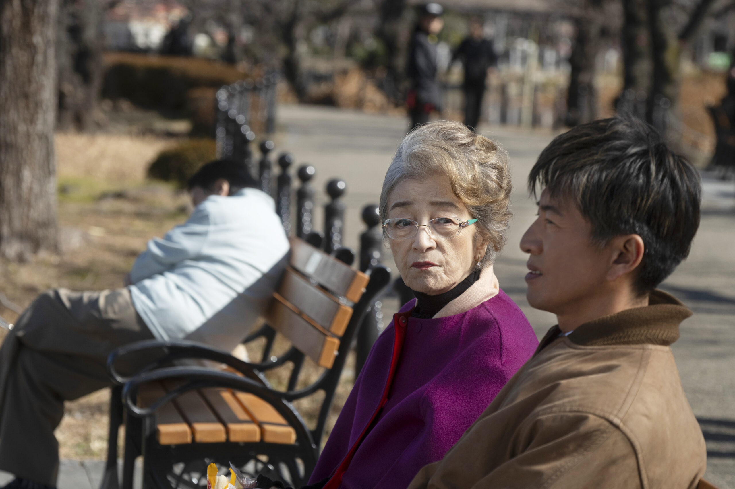 Chieko Baisho as Sumire Takano and Takuya Kimura as Koji Usami sitting on a park bench in Tokyo Taxi